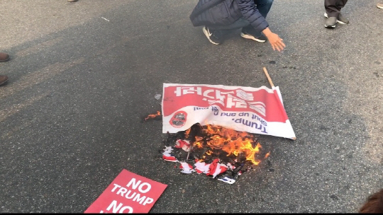 8일 서울 여의도 국회 앞에서 열린 트럼프 대통령 국회 연설 반대 집회에서 한 참가자가 ‘트럼프 물러가라’라고 적힌 깃발을 불태우고 있다. /이두형기자