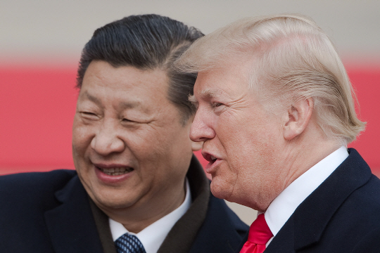 도널드 트럼프(앞쪽) 미국 대통령과 시진핑 중국 국가주석이 9일(현지시간) 미중 정상회담 장소인 베이징 인민대회당 앞에서 열린 환영행사 도중 밝은 표정으로 대화를 나누고 있다. 트럼프 대통령은 이날 중국으로부터 2,500억달러 규모의 투자 선물을 받고 중국에 대한 압박 수위를 낮췄다.   /베이징=AFP연합뉴스
