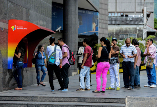 14일(현지시간) 베네수엘라 수도 카라카스에서 시민들이 돈을 찾기 위해 현금자동입출금기(ATM) 앞에 줄지어 서있다./카라카스=AP연합뉴스
