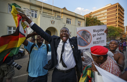 37년간 짐바브웨를 통치해 온 로버트 무가베 대통령의 사임 소식이 전해진 21일(현지시간)오후 수도 하라레의 의사당 앞에서 시민들이 환호하며 그의 퇴진을 기뻐하고 있다. /하라레=AP연합뉴스