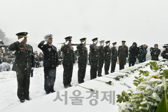 23일 눈이 내리는 가운데 치러진 연평도 포격전 7주기 추모행사에서 해군·해병대 장교들이 경례를 하고 있다.