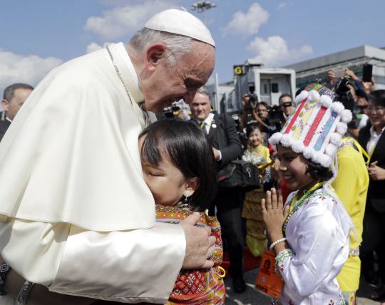 프란치스코(왼쪽) 교황이 27일 미얀마 양곤 국제공항에 도착해 현지 전통의상을 입은 아이와 포옹하고 있다.          /양곤=AP연합뉴스