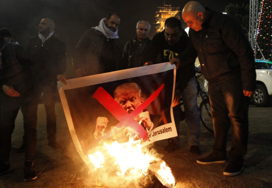 팔레스타인 주민들이 5일(현지시간) 베들레헴 광장에서 예루살렘을 이스라엘 수도로 인정하기로 한 도널드 트럼프 미 대통령 사진을 불태우며 시위하고 있다.  /베들레헴=AFP연합뉴스