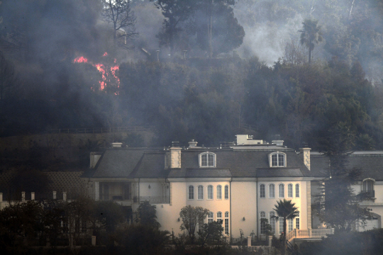 A Bel Aire mansion threatened by the Skirball Fire in west Los Angeles, California, December 6, 2017.  California motorists commuted past a blazing inferno Wednesday as wind-whipped wildfires raged across the Los Angeles region, with flames  triggering the closure of a major freeway and mandatory evacuations in an area dotted with mansions. / AFP PHOTO / Robyn Beck      <저작권자(c) 연합뉴스, 무단 전재-재배포 금지>