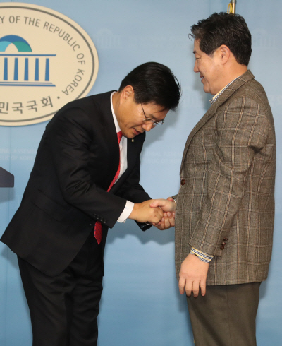 홍문종(왼쪽) 의원이 10일 후보단일화 기자회견을 마친 뒤 유기준 의원에게 고개 숙여 인사하고 있다. /연합뉴스