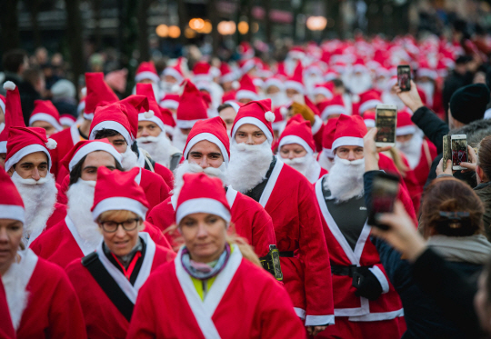 성탄절을 보름 앞둔 15일(현지시간) 스웨덴 스톡홀름 시민들이 자선행사 ‘산타 런(Santa Run)’의 광경을 카메라에 담고 있다. 이날 행사 참가자들은 산타 복장을 하고 스톡홀름 구시가지에서 행진했다. /스톡홀름=AFP연합뉴스