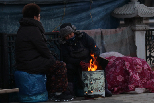 전북 전역 아침 최저기온이 영하권을 기록한 14일 오전 전주 남부시장에서 상인들이 불 앞에 모여 몸을 녹이고 있다./연합뉴스