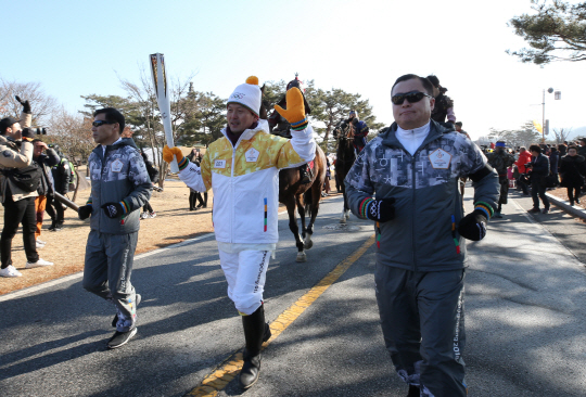 지난 21일 성화봉송 주자가 충북 충주에서 평창올림픽 성화를 들고 주민들과 함께 뛰고 있다. /연합뉴스