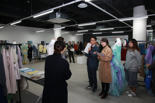 패션의류업계 관계자들이 22일 전시회에 출품한 와이즈유 패션디자인학과 학생들의 작품을 심사하고 있다./사진제공=와이즈유 영산대학교