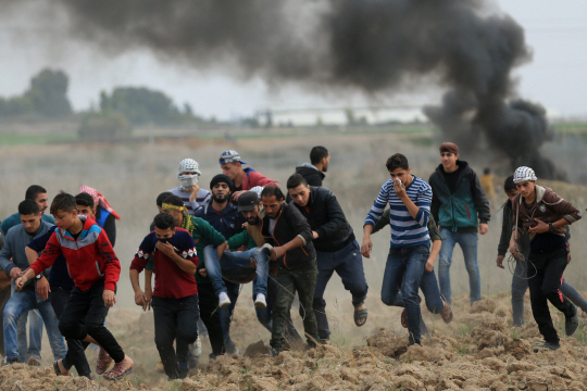 팔레스타인 시위대가 가자지구 국경 근처에서 이스라엘군과 출동로 부상당한 동료를 옮기고 있다. /AFP연합뉴스