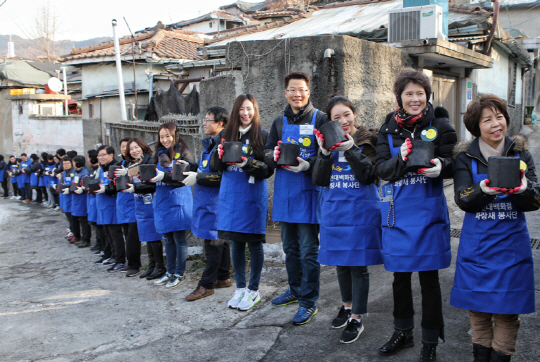 2일 현대백화점그룹 임직원들이 서울 노원구 중계동 백사마을에서 새해 첫 업무로 저소득층 가구에 전달할 연탄을 직접 나르고 있다. 현대백화점그룹은 이날 4,500장을 포함해 25만장의 연탄을 연탄은행에 전달했다.  /사진제공=현대백화점