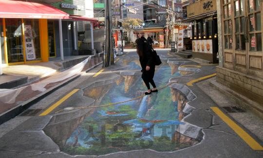서울 서대문구 신촌 도로에 그려진 착시그림 위를 한 시민이 걷고 있다. /사진제공=서대문구