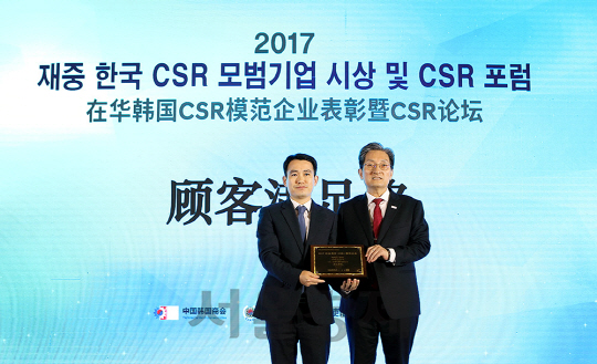 지난해 12월 중국 베이징 크라운플라자호텔에서 열린 ‘2017 재중 CSR 모범기업 시상 및 CSR 포럼’에서 박인복(왼쪽) 두산인프라코어 중국법인 부장이 노영민 주중한국대사로부터 상을 받고 있다./사진제공=두산인프라코어