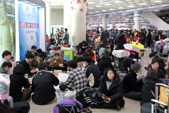 11일 제주공항에 내린 폭설로 항공편이 잇달아 결항하자 관광객들이 공항 대합실 바닥에 주저앉아 운항재개 소식을 기다리고 있다. 이날 제주·김포 등 전국 공항에서 총 140편의 항공기가 결항했다.  /제주=연합뉴스