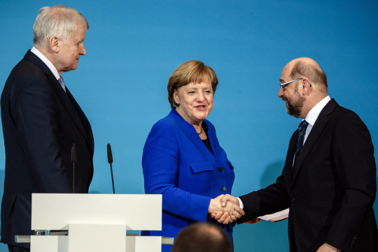 12일(현지시간) 앙겔라 메르켈(가운데) 독일 총리가 베를린에서 대연정 예비협상을 타결한 후 마틴 슐츠(오른쪽) 사회민주당 대표와 악수를 나누고 있다. /베를린=EPA연합뉴스