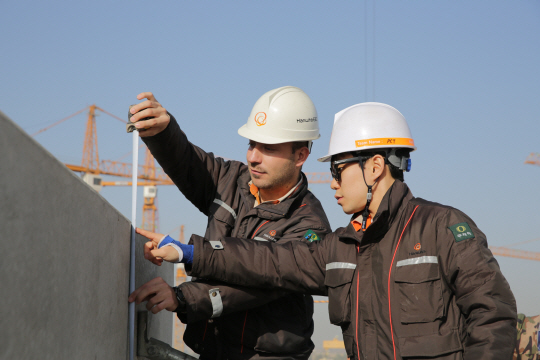 18일 일산 화정역 인근에서 진행되는 평창동계올림픽 성화봉송에 참여하는 한화건설의 오사마 아야드(왼쪽)씨가 이라크 비스마야 신도시 건설공사 현장에서 근무하고 있다. / 사진제공=한화건설