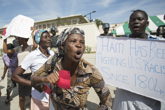 19일(현지시간) 아이티인들이 아이티의 수도 포르토프랭스에 위치한 미국 대사관앞에서 자국을 ‘거지소굴(shithole)’이라고 지칭한 트럼프 대통령을 규탄하는 시위를 벌이고 있다. 피켓에 “아이티는 1804년부터 미국의 인종차별주의와 싸우고 있다”는 문구가 적혀있다. /포르토프랭스=AFP연합뉴스