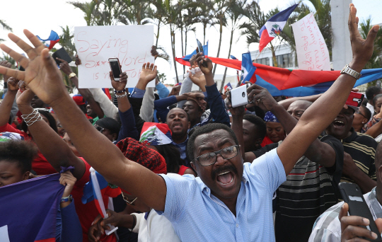 미국 아이티계 주민들이 15일(현지시간) 플로리다주 팜비치에 위치한 도널드 트럼프 대통령의   개인별장 마러라고 리조트 근처에서 자국을 ‘거지소굴(shithole)’이라고 지칭한 트럼프 대통령을 규탄하는 시위를 벌이고 있다. /팜비치=AFP연합뉴스