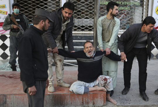 28일 아프카니스탄 수도 카불에서 구급차를 이용한 대형 테러가 발생한 가운데 시민들이 울부짖는 한 부상자를 옮기고 있다./AP연합뉴스