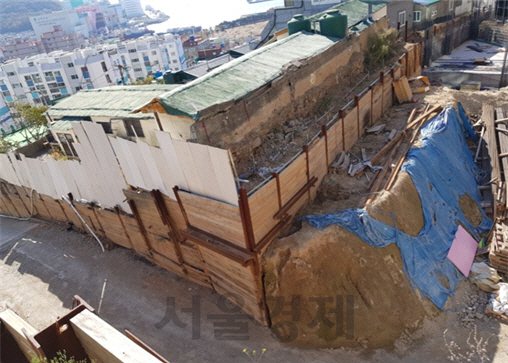 부산 사하구의 아파트 공사과정에서 사용하던 도로가 3m 가량 깎여 집 앞이 절벽이 된 모습.