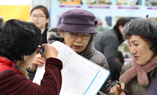 6일 서울시 마포구청에서 열린 ‘2018 노인 일자리 및 사회활동지원사업 통합모집’ 행사에 참석한 노인들이 일자리 관련 신청서를 살펴보고 있다. /연합뉴스