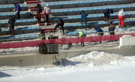 대회 관계자들이 알펜시아 스키점프센터 관중석의 얼음과 눈을 제거하고 있다.   /평창=연합뉴스