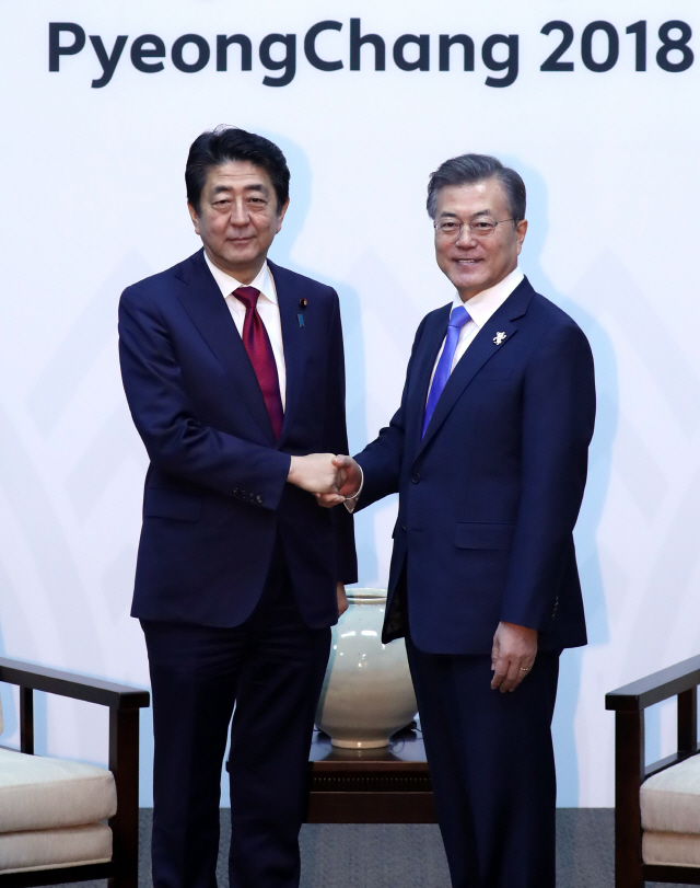 문재인(오른쪽) 한국 대통령과 아베 신조(왼쪽) 일본 총리가 평창올림픽 개막식이 열리는 9일 오후 강원도 용평 블리스힐스테이에서 만나 악수하고 있다.    /평창=연합뉴스