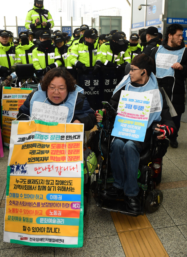 설 연휴를 하루 앞두고 수많은 귀성객이 서울역을 찾은 14일 전국장애인차별철폐연대 관계자들이 KTX 승차장에서 장애인의 이동권 보장을 촉구하며 구호를 외치고 있다.         /송은석기자