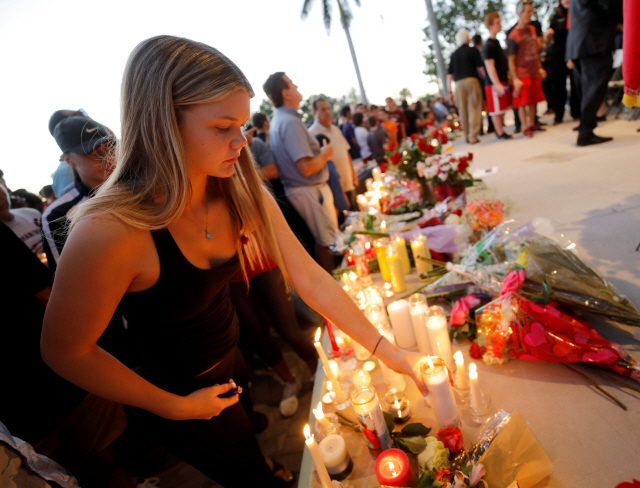 미국 플로리다주 마조리 스톤맨 더글라스 고등학교에서 15일(현지시간) 총기 사격으로 17명이 숨지는 등 다수의 사상자가 발생한 가운데 한 학생이 16일 현지에서 열린 희생자 추모회에 참석해 촛불을 켜고 있다. /파크랜드=로이터연합뉴스