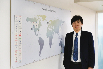 윤영호 산돌커뮤니케이션 대표가 서울 종로구 명륜동 본사에서 세계 지도에서 글로벌 기업 고객들의 위치를 가리키며 소개하고 있다./사진제공=산돌커뮤니케이션