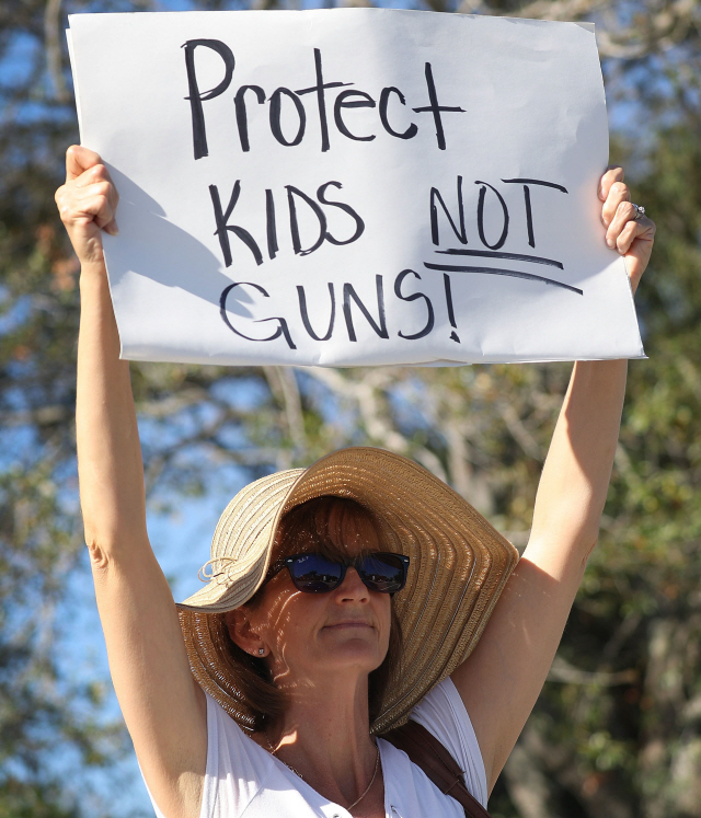 총기난사 사건이 발생한 플로리다주 파크랜드시에서 한 시민이 17일(현지시간) ‘총이 아닌 아이들을 보호하라’는 피켓을 높이 들고 있다.     /파크랜드=AFP연합뉴스