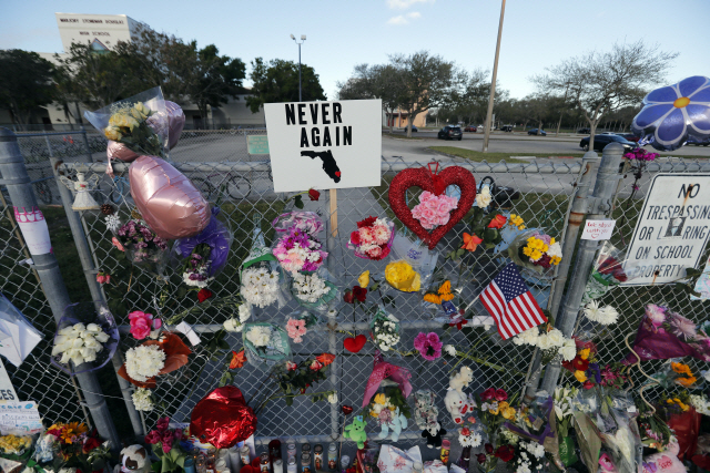 19일(현지시간) 미국 플로리다주 파크랜드에 있는 마조리 스톤맨 더글러스 고등학교 시설물에 꽃다발들이 걸려있다. 지난 14일 이 학교에서 총기 참사가 발생해 17명이 목숨을 잃었다. /파크랜드=AP연합뉴스