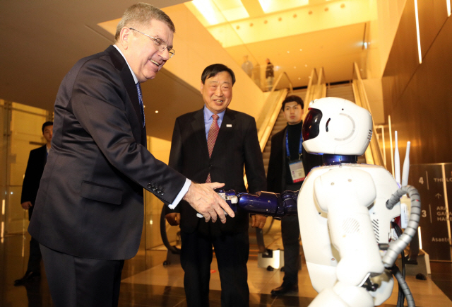 토마스 바흐(왼쪽) IOC 위원장이 강릉 씨마크호텔에서 열린 IOC 집행위원 만찬에 참석하며 로봇과 악수하고 있다.    /연합뉴스