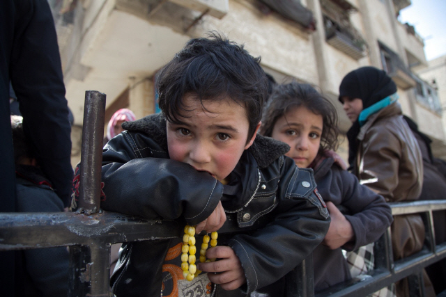 Syrian children sit in the back of a truck driven by White Helmets, as they flee their homes in the town of Beit Sawa in Syria‘s besieged eastern Ghouta region on March 4, 2018, following reported air strikes.  Syria’s regime seized control of over a quarter of rebel-held Eastern Ghouta on the edge of Damascus after two weeks of devastating bombardment, sending hundreds of civilians into flight, the Syrian Observatory for Human Rights said.   / AFP PHOTO / ABDULMONAM EASSA      <저작권자(c)