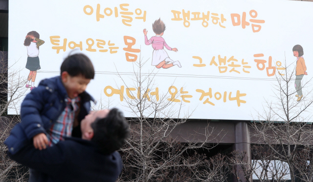 5일 서울 광화문 교보생명 빌딩에 새로 내걸린 광화문글판 앞에서 한 가족이 즐거운 시간을 보내고 있다. 새 글판 ‘봄편’은 김광규 시인의 ‘오래된 물음’에서 가져왔다./권욱기자