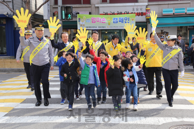 어린이 보행 안전을 위해 7일 서울 종로구 제동초등학교서 개최된 ‘엄마손캠페인’에 참여한 어린이들이 엄마손 피켓을 들고 횡단보도를 건너고 있다. /사진제공=KB손해보험