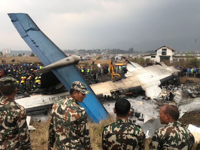 네팔 군·경찰 인력들이 12일(현지시간) 파트만두 공항 인근에 추락한 방글라데시 여객기 추락사고 현장을 조사하고 있다. /카트만두=로이터연합뉴스