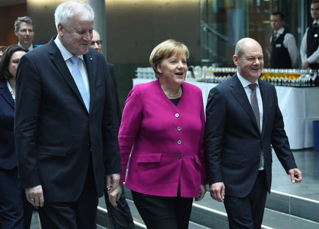 앙겔라 메르켈(가운데) 독일 총리가 올라프 숄츠(오른쪽) 사회민주당 대표, 호르스트 제호퍼(왼쪽) 기독사회당 대표와 12일(현지시간) 베를린의 대연정 최종 합의안 서명식장에 입장하며 밝게 웃고 있다. 메르켈 총리는 “마침내 일할 시간이 왔다”며 “우리는 역동적이고 성공적인 유럽을 위해 힘을 합치겠다”고 말했다. 14일 연방하원이 메르켈 총리 연임안을 가결하면 지난해 9월 총선 이후 다섯 달 만에 정부가 정식 출범하게 된다.      /베를린=EPA연합뉴스
