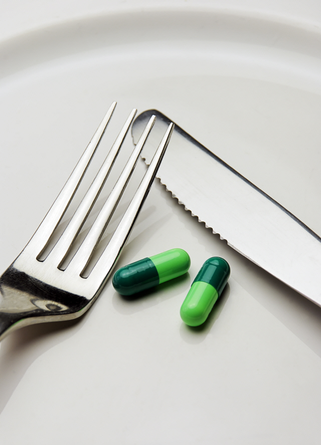 supplement capsules set on a white plate with knife and fork