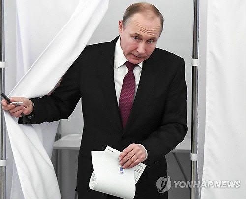 러시아 대선이 18일(현지시간) 극동지역에서부터 일제히 시작된 가운데 블라디미르 푸틴 대통령이 모스크바의 한 투표소에서 투표용지에 기표한 뒤 나오고 있다. /모스크바 AP=연합뉴스