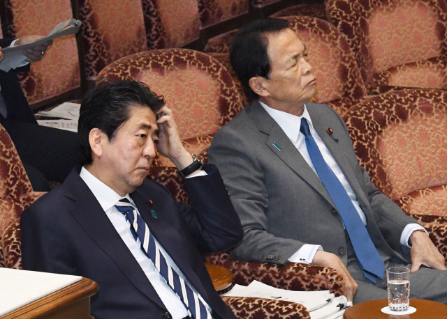 아베 신조(왼쪽) 일본 총리와 아소 다로 부총리 겸 재무상이 19일 도쿄의 참의원 예산위원회에 출석해 사학스캔들과 관련한 의원들의 질의를 들으며 침통한 표정으로 앉아 있다.      /도쿄=교도연합뉴스