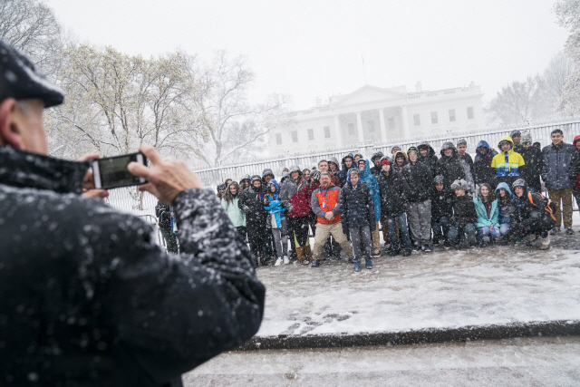 관광객들이 21일(현지시간) 눈이 내리는 백악관 앞에서 기념 촬영을 하고 있다./EPA연합뉴스