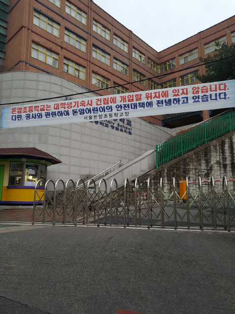 서울 성북구 동소문동에 위치한 돈암초등학교 정문에 행복기숙사 건립에 개입하지 않겠다는 학교의 입장을 담은 플래카드가 걸려있다./백주연기자
