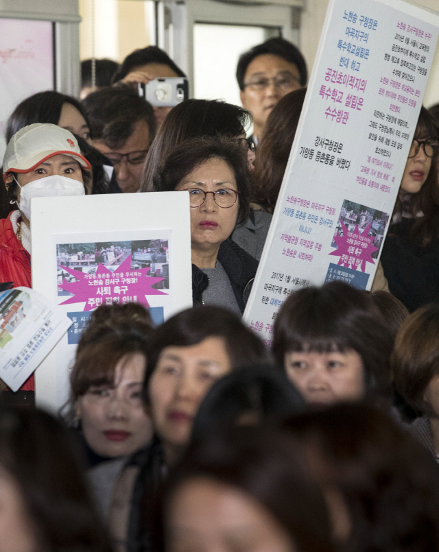 26일 오전 서울 강서구 옛 공진초 터에서 열린 특수학교 설립추진 설명회에서 특수학교 설립을 반대하는 주민들이 관련 내용이 적힌 피켓을 들고 서 있다./연합뉴스