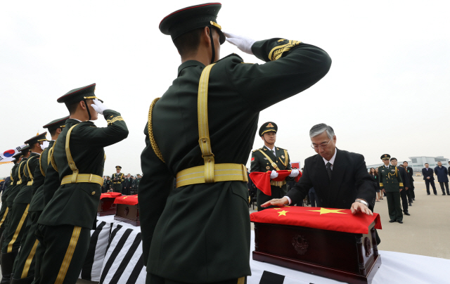 28일 오전 인천국제공항 계류장에서 열린 제5차 중국군 유해 인도식에서 추궈홍 주한중국대사가 유해가 담긴 관에 중국국기를 덮고 있다.  /연합뉴스