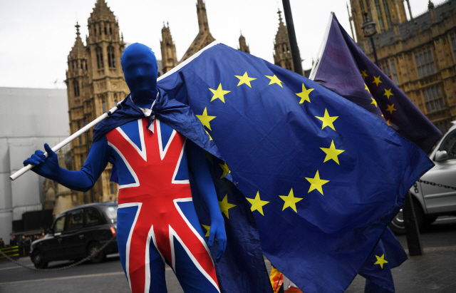브렉시트(영국의 유럽연합 탈퇴, Brexit) 1주년을 맞은 29일(현지시간) 런던 국회의사당 앞에서 한 남성이 유럽연합(EU) 깃발을 들고 브렉시트 반대시위를 벌이고 있다. 이날 테리사 메이 총리는 브렉시트 이후 영국의 통합을 강조하기 위해 스코틀랜드·잉글랜드·웨일스·북아일랜드 등 연방 4개국 순방에 나섰다.    /런던=EPA연합뉴스