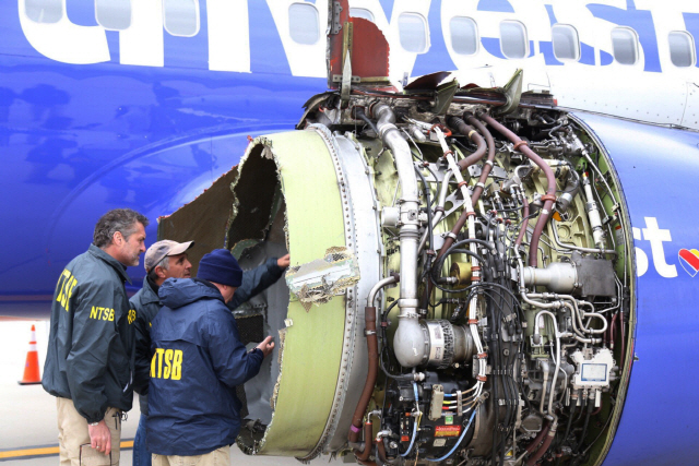 National Transportation Safety Board investigators examine damage to the engine of the Southwest Airlines plane that made an emergency landing at Philadelphia International Airport in Philadelphia on Tuesday, April 17, 2018. The Southwest Airlines jet blew the engine at 32,000 feet and got hit by shrapnel that smashed a window, setting off a desperate scramble by passengers to save a woman from getting sucked out. She later died, and seven others were injured. (NTSB via AP)      <저작권자(c) 연합뉴스, 무단 전재-재배포 금지>