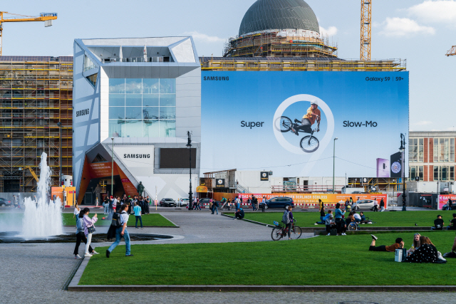 독일 시민들이 베를린 시티 팰리스에 걸려 있는 삼성전자 갤럭시 S9의 광고물 앞 잔디에서 쉬고 있다. /사진제공=삼성전자