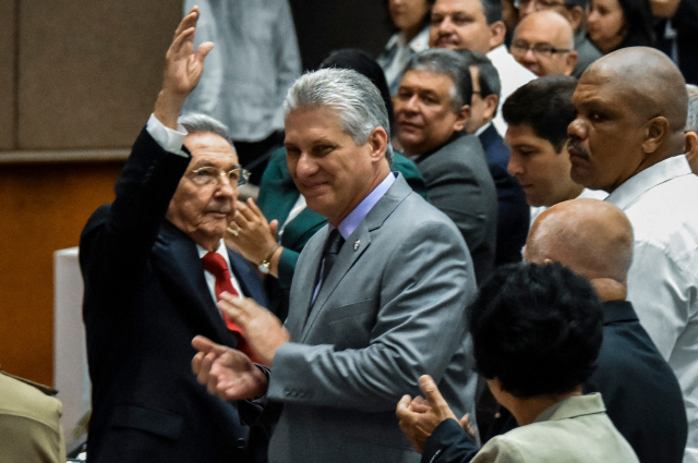 라울 카스트로(왼쪽) 쿠바 국가평의회 의장이 18일(현지시간) 아바나에서 열린 전국인민권력회 총회에서 참석자들의 환호에 답하며 손을 들어 올리자 미겔 디아스카넬(가운데) 국가평의회 수석부의장이 박수를 치고 있다.  /아바나=AFP연합뉴스