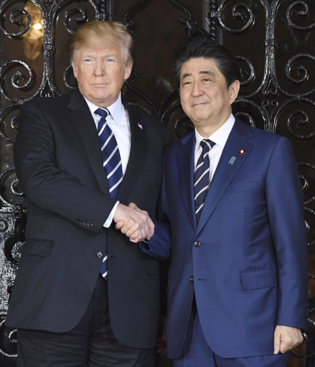 도널드 트럼프(왼쪽) 미국 대통령이 정상회담을 위해 방미한 아베 신조 일본 총리를 지난 17일 플로리다주 팜비치의 마러라고 리조트에서 만나 악수하고 있다. 이날 두 정상은 같은 색·무늬의 넥타이를 매 화제가 됐다.   /팜비치=교도연합뉴스
